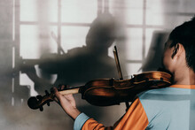Rear View Of Boy Playing Violin Against Wall