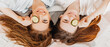 © Daria Lukoiko - Two girls make homemade face and hair beauty masks. Cucumbers for the freshness of the skin around the eyes. Women take care of youthful skin. Girlfriends laugh at home lying on the floor on pillows.