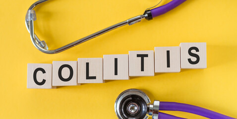 Wall Mural - COLITIS the word on wooden cubes on yellow background, near cubes - a stethoscope. Medicine concept