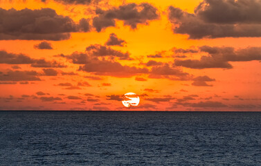 Wall Mural - brilliant sun setting over ocean with ckouds
