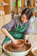 © evafesenuk - Master class on modeling of red clay on a potter's wheel in the pottery workshop