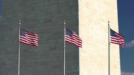 Wall Mural - Flags of the United States near washington monument waving over blue sky