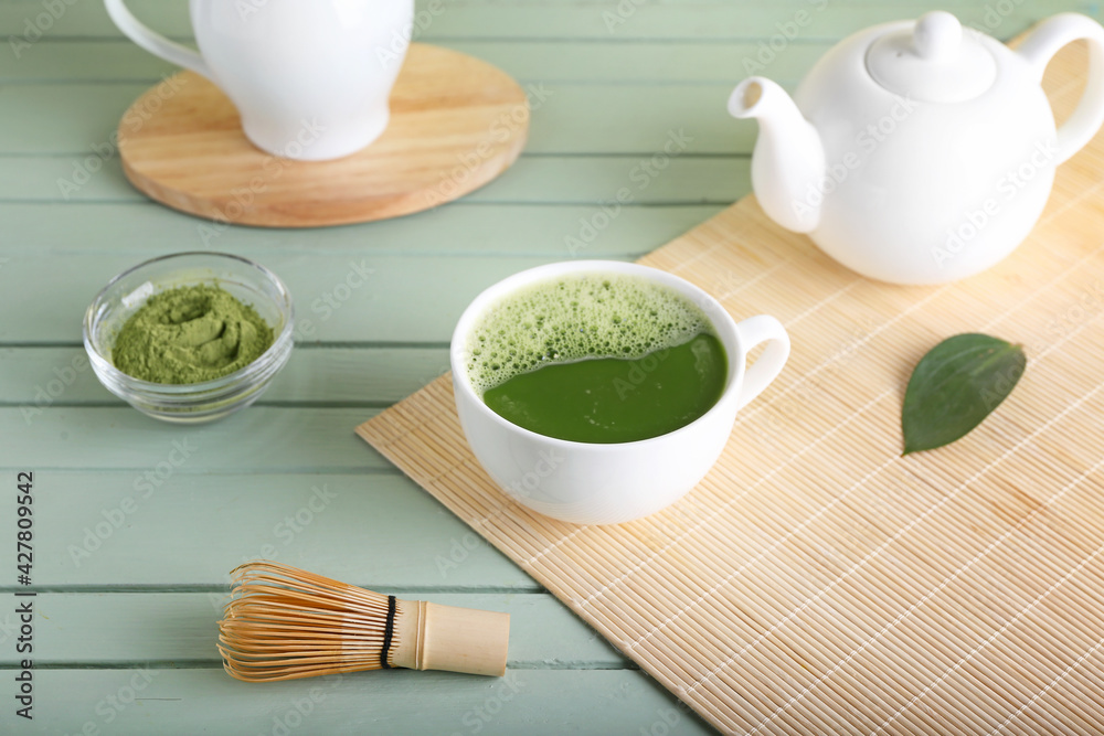 Composition with cup of matcha tea on color wooden background