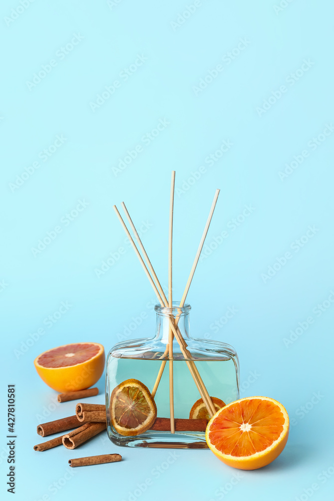 Reed diffuser with cinnamon and oranges on color background