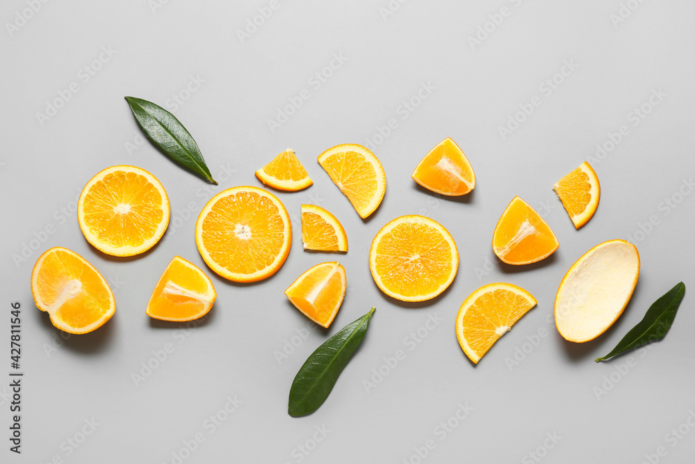 Fresh orange slices with leaves on light background