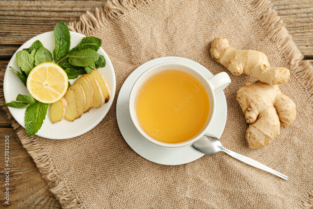 Cup of tea with ginger, mint and lemon on wooden background