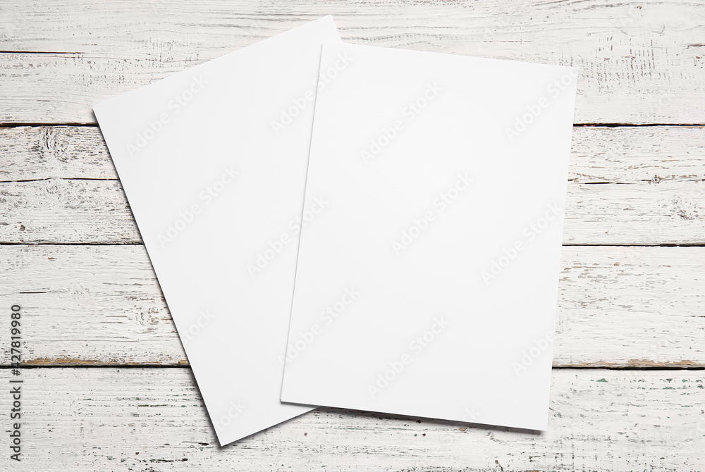 Blank sheets of paper on light wooden background