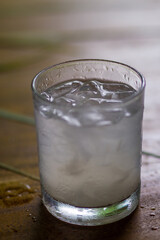 Poster - Vertical shot of a glass full of ice water on wooden table