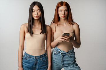 Wall Mural - Two young multiethnic women standing posing together