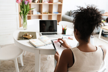 Black woman working with laptop and papers while sitting at table