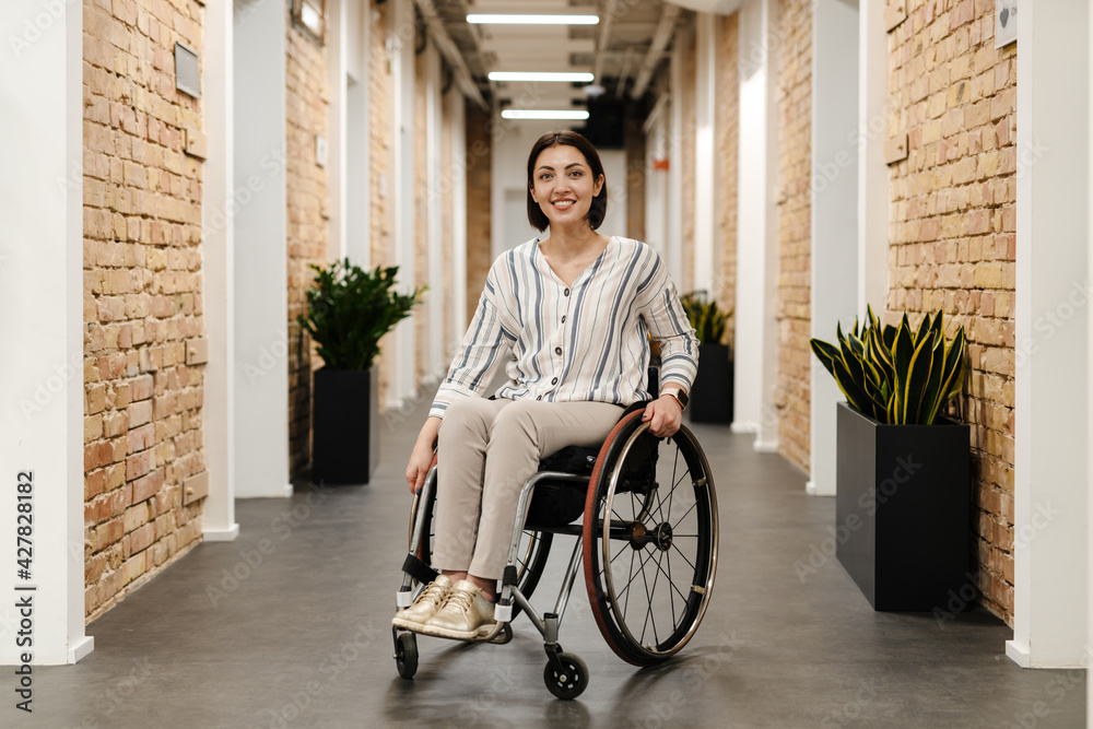 White young woman smiling while sitting in wheelchair at office Stock ...