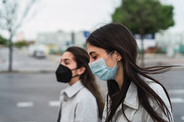 Dos amigas con chaqueta vaquera paseando con mascarilla por la calle