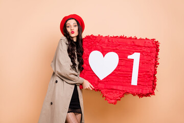 Poster - Photo portrait of woman kissing holding big red like pinata isolated on pastel beige colored background