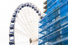 Large Modern Spinning Ferris Wheel Stands Next To A Building Construction Site In A Blue Protective Cover Next To The Town's New Buildings In Dresden, Germany. Architecture And Travel Concept