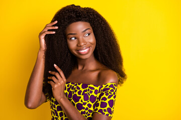 Wall Mural - Portrait of attractive feminine cheerful dreamy girl touching silky hair isolated over bright yellow color background