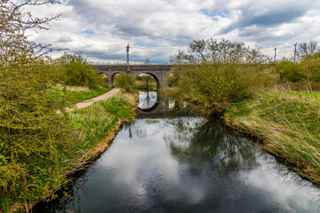 A view along the River Nene towards the Far Cotton Railway viaduct in Northampton, UK on a bright Spring day