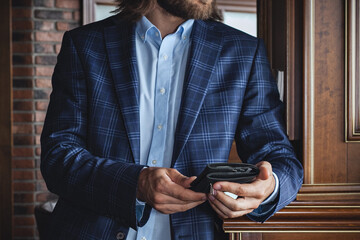 A businessman in a shirt and jacket with a wallet in his hands on the background of the interior. Horizontal orientation, no face