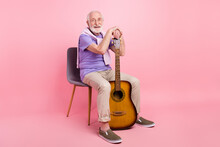 Full Length Body Size Grandpa Keeping Guitar Sitting On Chair Casual Outfit Isolated On Pastel Pink Color Background