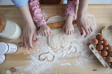 mother and daughter in the kitchen prepare food from flour, and draw hearts on flour