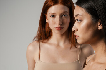 Wall Mural - Multiracial young two women posing while looking at camera and aside