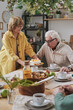 © AnnaStills - Senior woman bringing birthday cake for her husband while he sitting at dining table at home