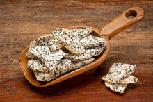 Slices Of Dried White Dragon Fruit In A Rustic Wooden Scoop Against Weathered Wood
