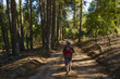 © LUMA - Young woman with hat walking along a forest path at sunset