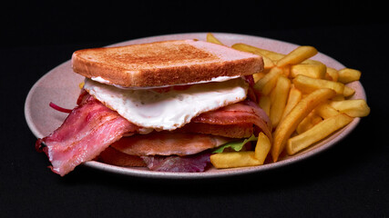 Poster - Top view of a double club sandwich with french fries on a plate isolated on black background