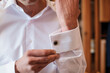The man fastens the cufflink on the sleeve of his shirt. The groom fastens a button on the sleeve of his shirt
