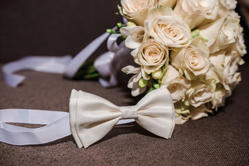 Wall Mural - White bow tie and a bouquet with white roses on a brown background