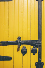 Vertical Shot Of A Yellow Door With A Metal Lock