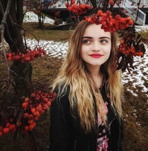 Teenage Young Woman With Red Lipstick Under A Tree With Fall Foliage, Smiling Off In The Distance