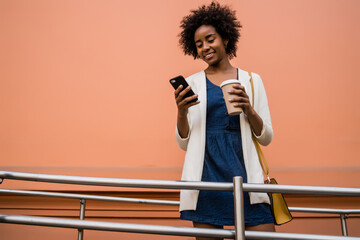 Wall Mural - Business woman using her mobile phone outdoors.