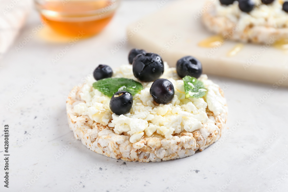 Crispbread with cottage cheese and blueberries on light background