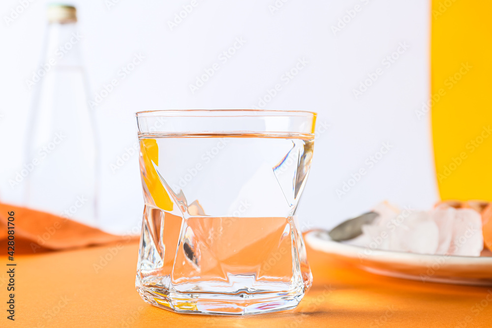 Glass of water on color background