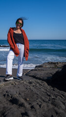 Poster - Vertical shot of a beautiful Hispanic woman with on the blue sea background in Chile