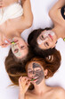 © Viorel - Home spa. Three women holding pieces of cucumber on their face lying down. Beauty salon concept, health.