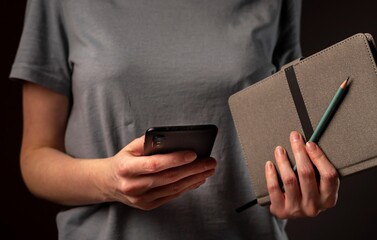 Poster - Female hands holding phone and making appointments, holding planner. Student using smartphone and notebook at night