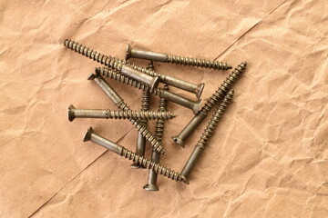 Several metal screws on craft paper, close-up, top view.