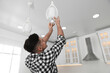 © New Africa - Man changing light bulb in lamp at home