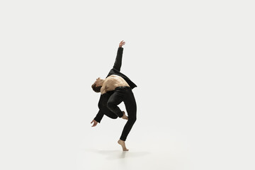 Man in casual style clothes jumping and dancing isolated on white background. Art, motion, action, flexibility, inspiration concept. Flexible caucasian ballet dancer.