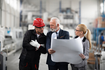 Architects and worker working on project. Colleagues working in factory.