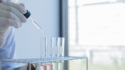 Medical or scientific researcher or man doctor looking at a test tube of clear solution in a laboratory