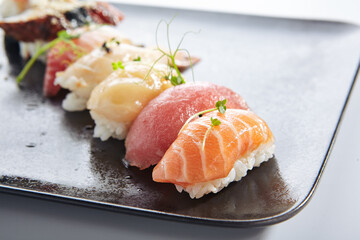 Canvas Print - Japanese Nigiri Sushi Set - Sushi with Rice and Various Seafood. Salmon, Tuna, Sea Scallop and other seafood fish. Nigiri Sushi row on black slate platter. Isolated on white background.