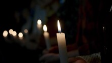 Close Up Of People Sitting In A Row And Holding Burning Candles. Stock Footage. Religious Background With Men And Women With Candles In A Dark Room.