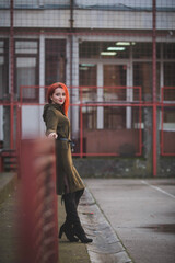 Poster - Attractive young Caucasian female with red hair in a green dress posing on a street