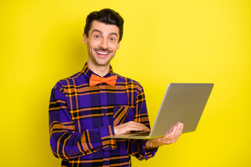 Poster - Photo of happy smiling good mood smiling lovely man working in laptop programmer isolated on yellow color background