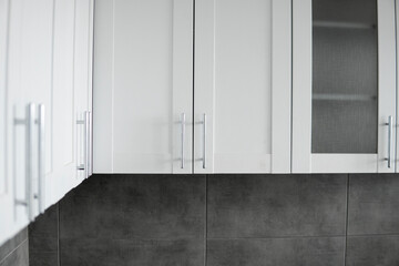 Modern minimalism style kitchen interior in monochrome tones. Custom kitchen with grey white facadesmdf and dark grey countertop with installed kitchen hood and sink. Modular kitchen from chipboard.