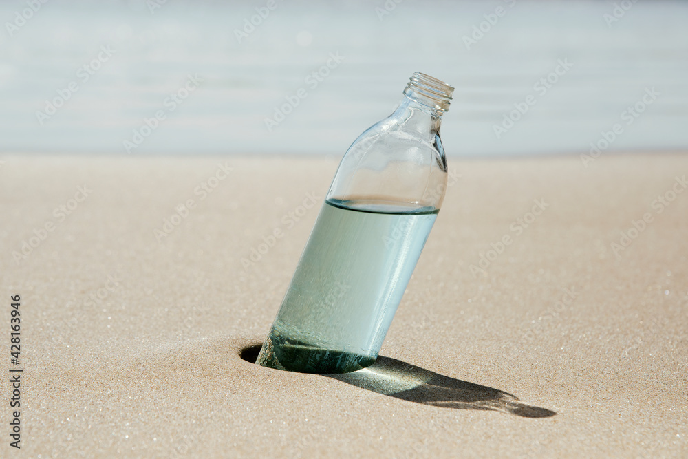 reusable water bottle on the sand of a beach - obrazy, fototapety, plakaty 