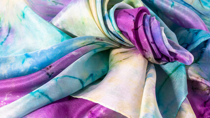 Multicolored silk fabric folded in beautiful waves close up.  Silk texture, wallpaper, background.